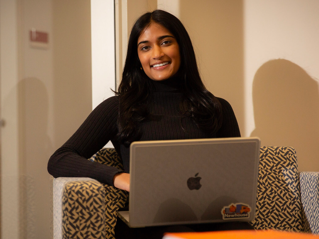 Smiling student using a laptop in a chair.