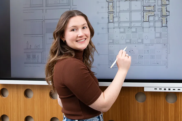 Woman pointing at architectural floor plans on a digital screen