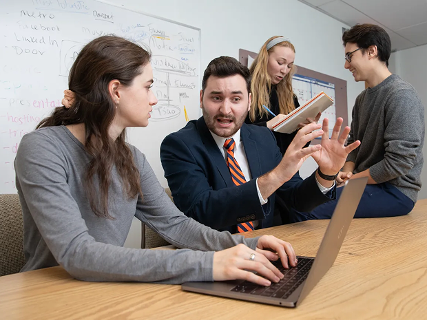 Students collaborating with an instructor using a laptop.