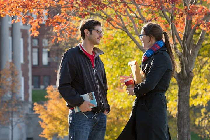 Two students talking outdoors in fall.