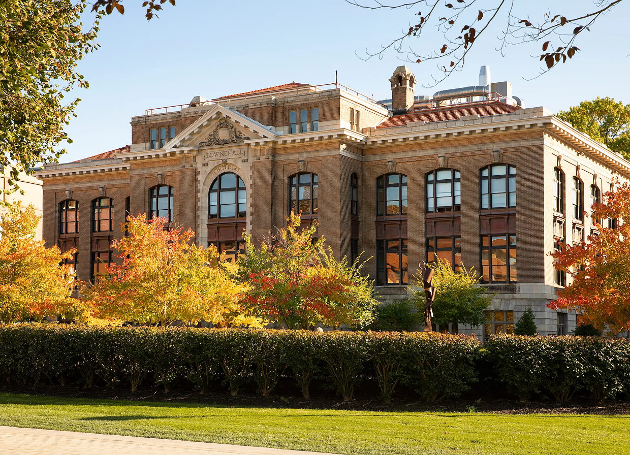 Campus building surrounded by trees with fall foliage.